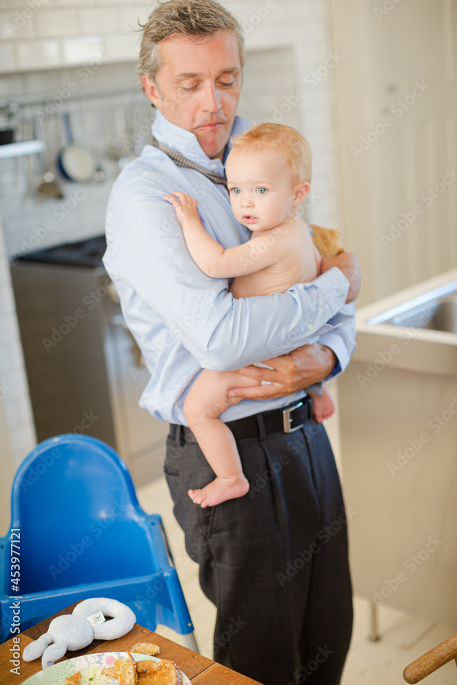 Father holding baby and eating breakfast
