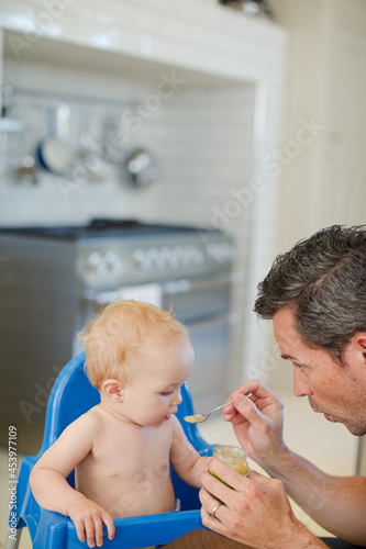 Father feeding baby in high chair