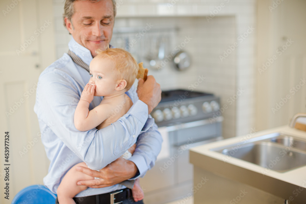 Father holding baby and eating breakfast Father holding baby and eating breakfast