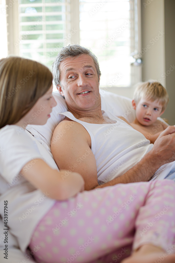 Father and children using digital tablet on bed Father and children using digital tablet on bed
