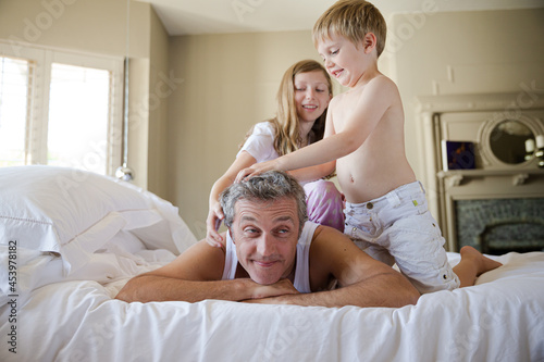 Father and children playing on bed