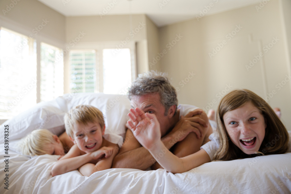 Father and children relaxing on bed