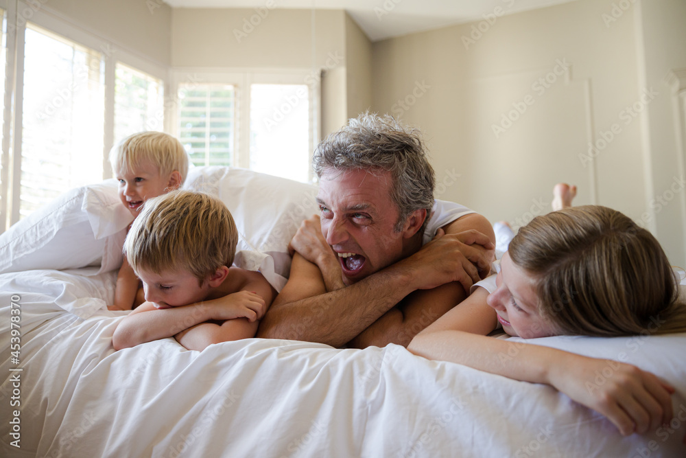 Father and children relaxing on bed