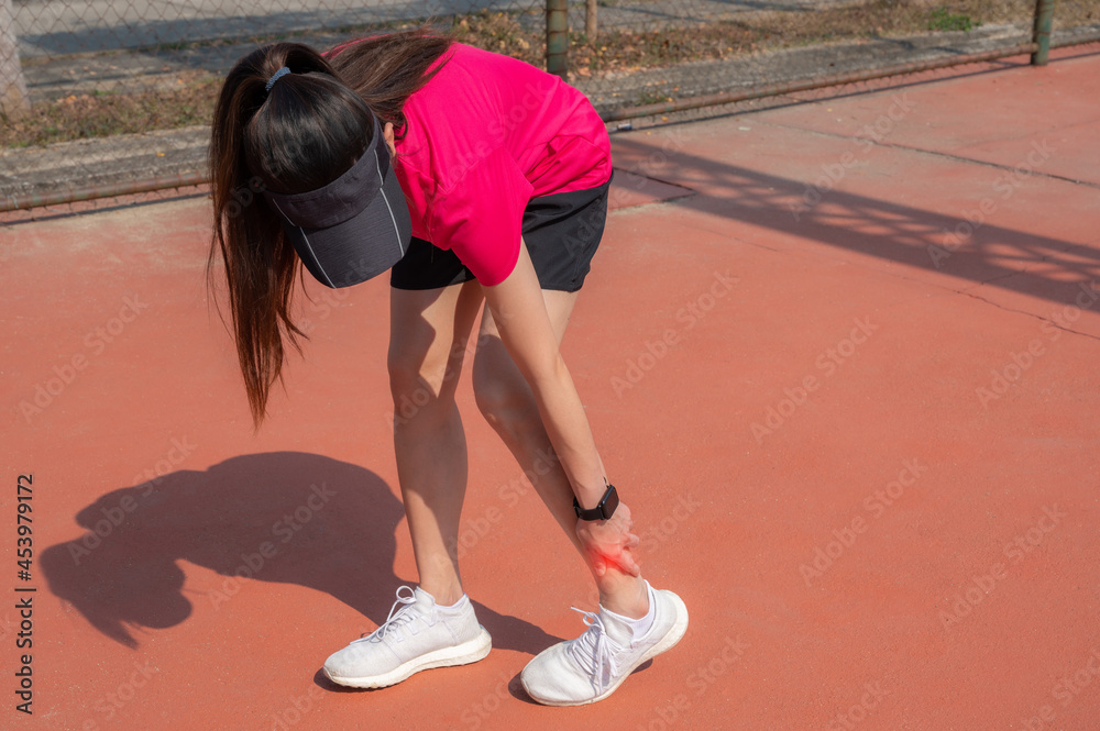 Runner woman touching her ankle while suffering from ankle pain. Ankle pain may be caused by an injury, like a sprain, or by a medical condition, such as arthritis.