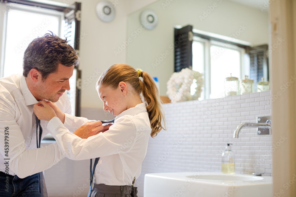 Obraz premium Father and daughter tying ties in bathroom