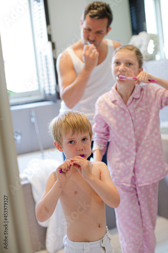 Father and children brushing teeth in bathroom