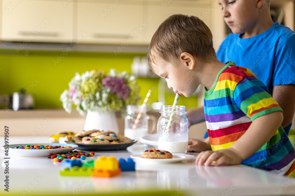 Funny male brothers eat cookies with round multi-colored sweets m&m and drink milk. Funny male brothers eat cookies with round multi-colored sweets m&m and drink milk.