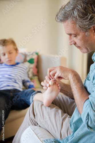Father bandaging son's foot