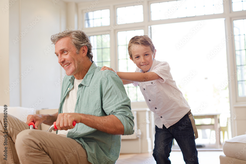 Fototapeta premium Boy pushing father on tricycle indoors