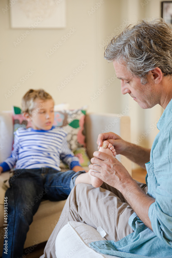 © KOTO - Father bandaging son's foot