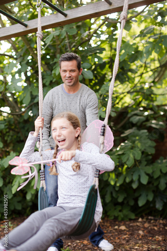 Father pushing daughter in swing © KOTO