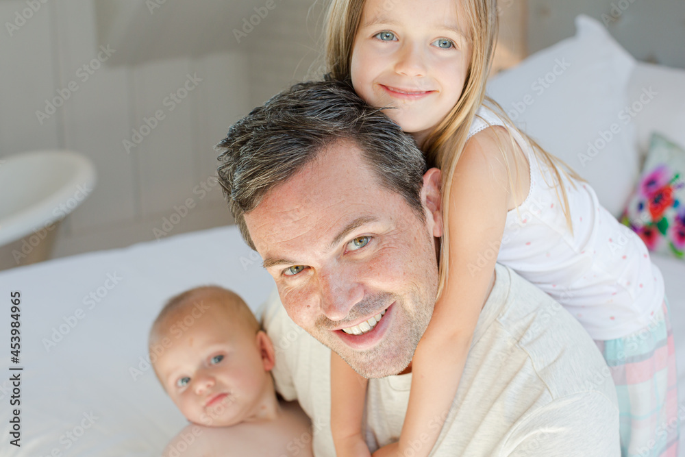 Father and children hugging in bedroom Father and children hugging in bedroom