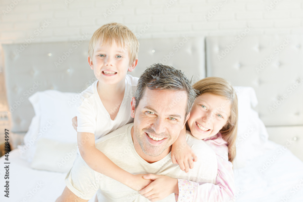 Father and children hugging in bedroom Father and children hugging in bedroom