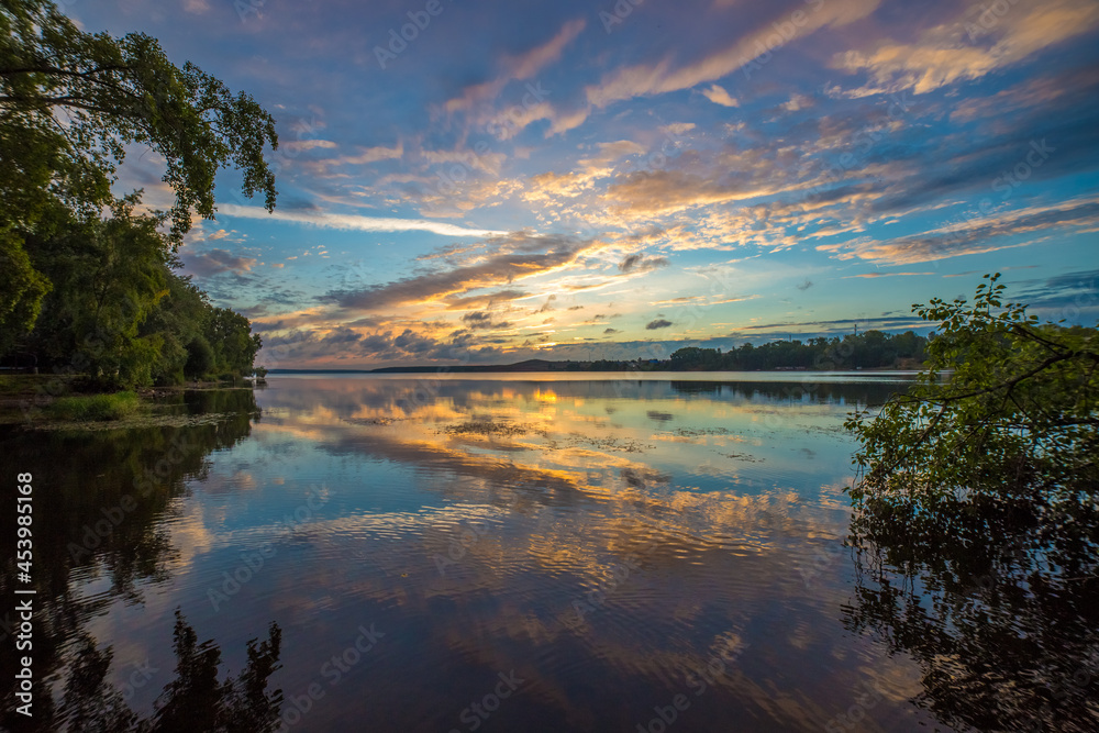 beautiful landscape of the water surface of the lake on a summer morning with light clouds in the sky reflecting in the water