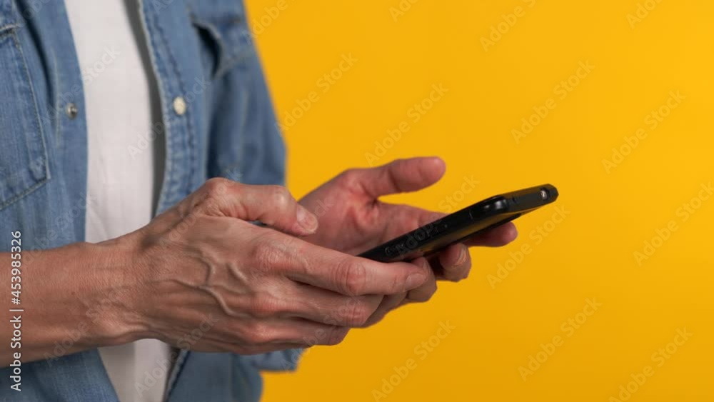 Middle aged Asian woman using smartphone isolated on yellow background Middle aged Asian woman using smartphone isolated on yellow background