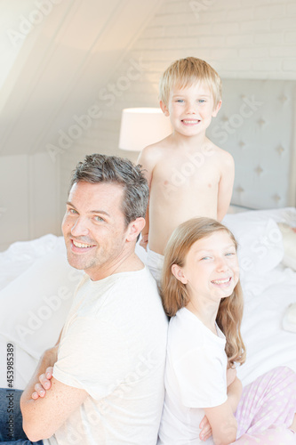 Father and children smiling on bed