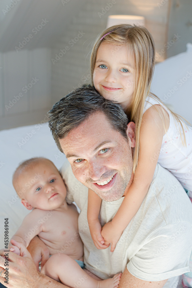 Father and children hugging in bedroom