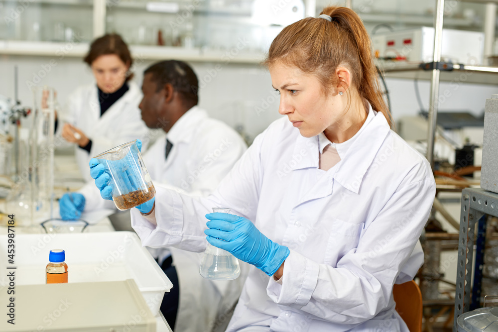 Young woman scientist working in research laboratory performing experiments in laboratory