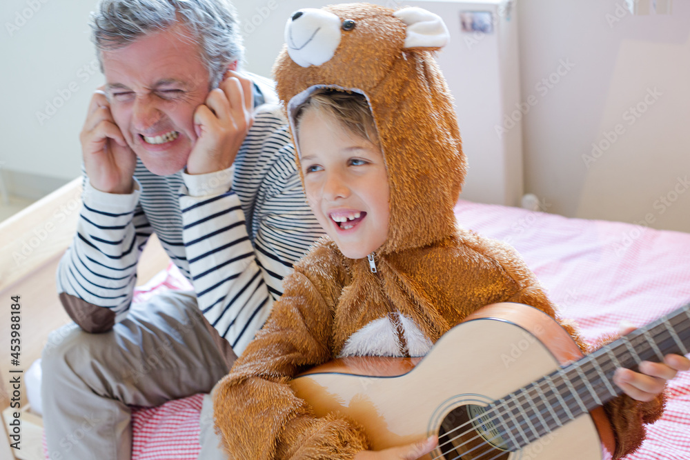 Father covers his ears when son playing guitar Father covers his ears when son playing guitar