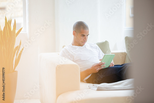 Man using digital tablet on sofa © KOTO