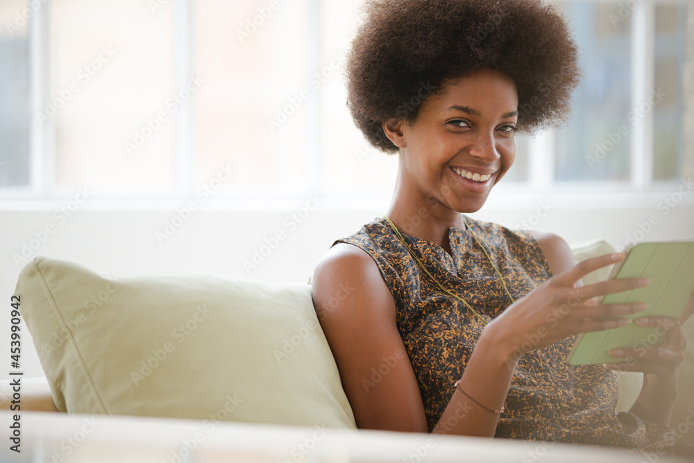 Woman using digital tablet on sofa