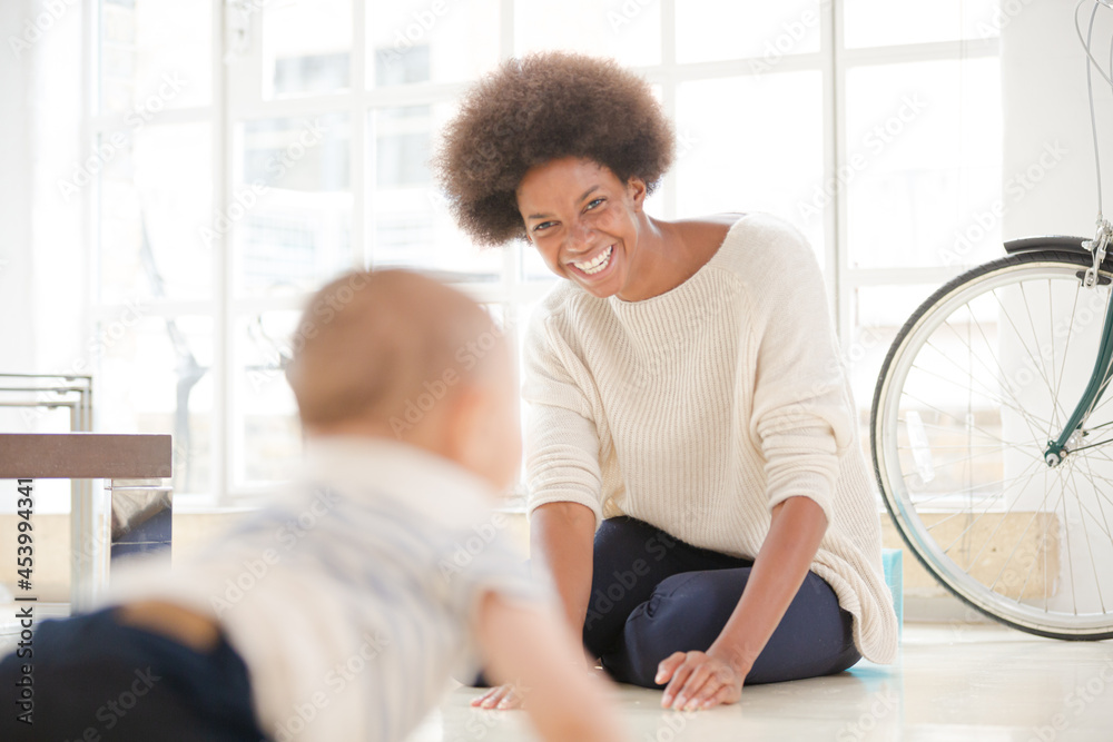 Obraz premium Mother watching baby boy crawl on floor