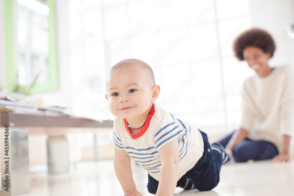 Mother watching baby boy crawl on floor Mother watching baby boy crawl on floor