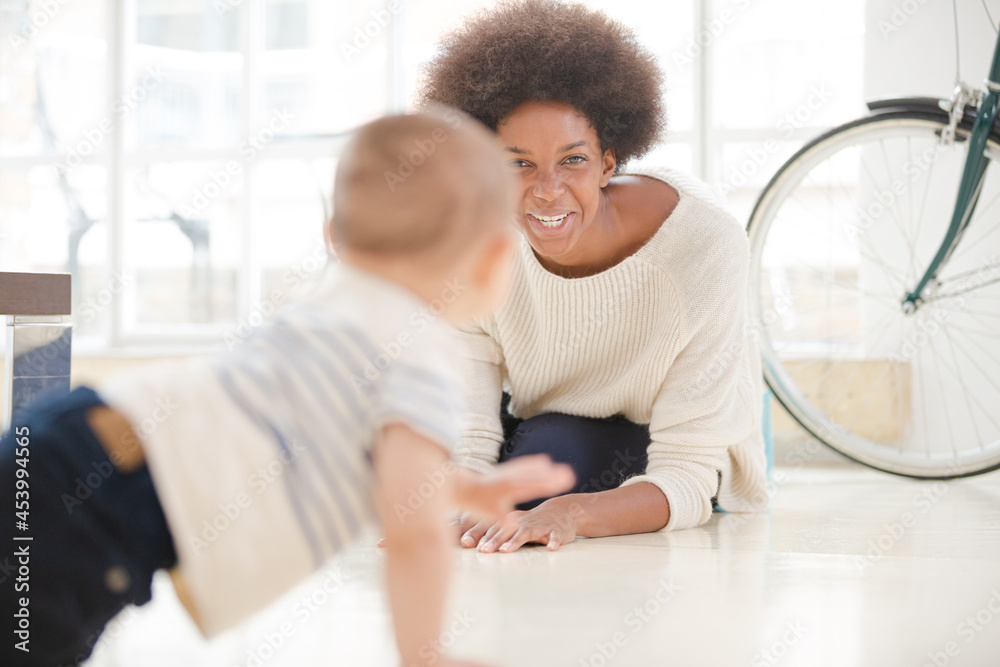 Obraz premium Mother watching baby boy crawl on floor