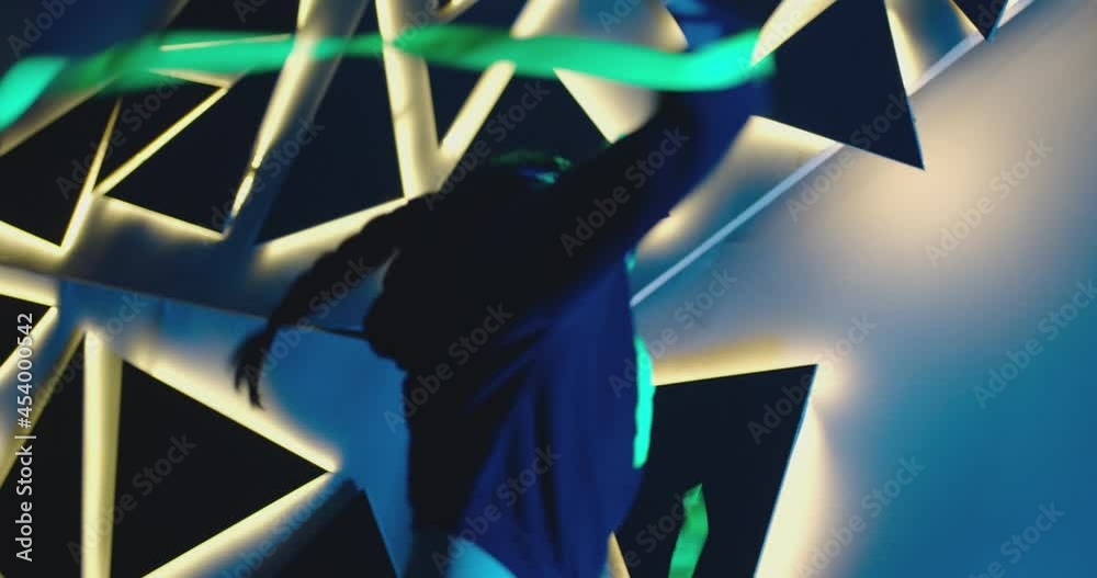 4K Footage of professional swag, freestyle or hip hop female dancer . Stylish young masked girl dancing against colorful background with triangle shape of led lights . Shot on ARRI ALEXA Camera .