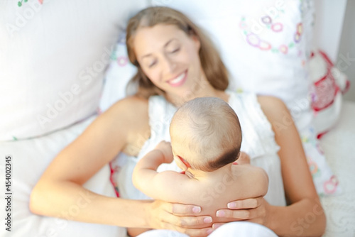 Mother holding baby boy on bed