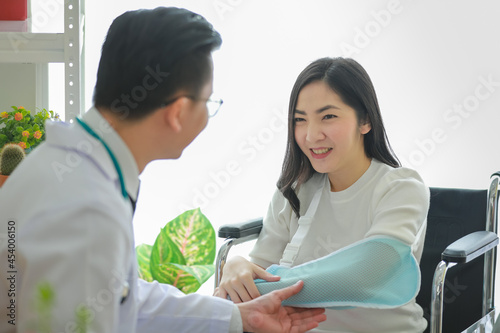 Doctor helping Asian patient with arm sling