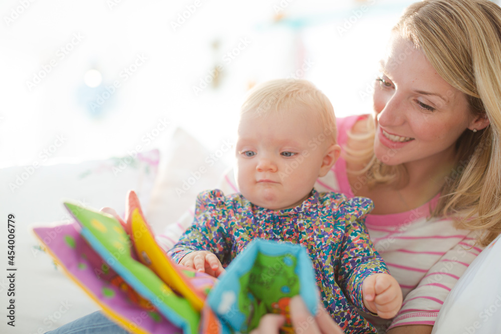 Mother reading to baby girl on sofa Mother reading to baby girl on sofa