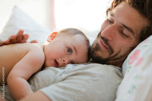 Father laying with baby boy on bed