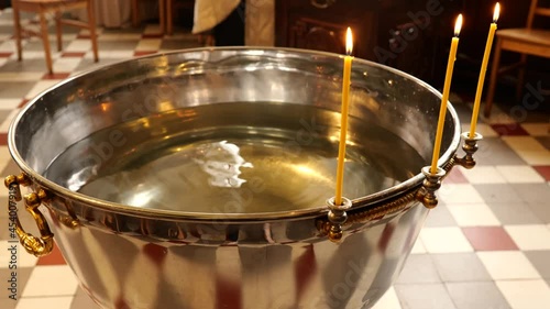 Orthodox baptism bowl of holy water with candles photo