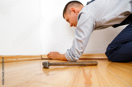 To make repairs. Installing a new skirting board. a man makes repairs in a room