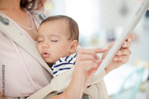 Fotografija Mother with sleeping baby girl using digital tablet