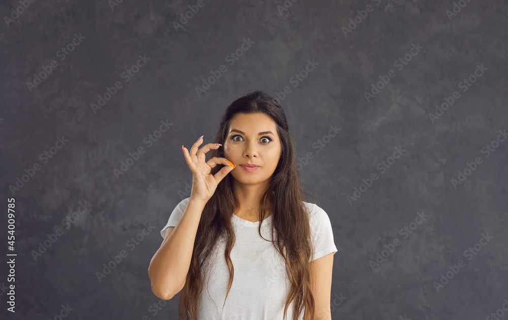 Headshot portrait of young Hispanic woman on black studio background keep finger at lips ask be quiet. Millennial gen z girl look at camera make hand gesture sign about secret deal or offer. Headshot portrait of young Hispanic woman on black studio background keep finger at lips ask be quiet. Millennial gen z girl look at camera make hand gesture sign about secret deal or offer.