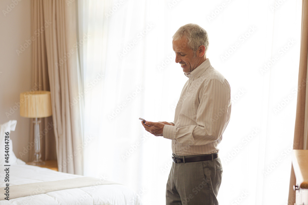 Fototapeta premium Businessman using cell phone in hotel room