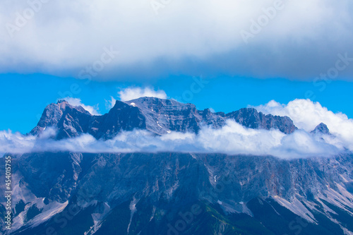 Zugspitze mountain massif disappearing in fog and clouds with dramatic sky. Copy space. Template for travel and tourism concept.
