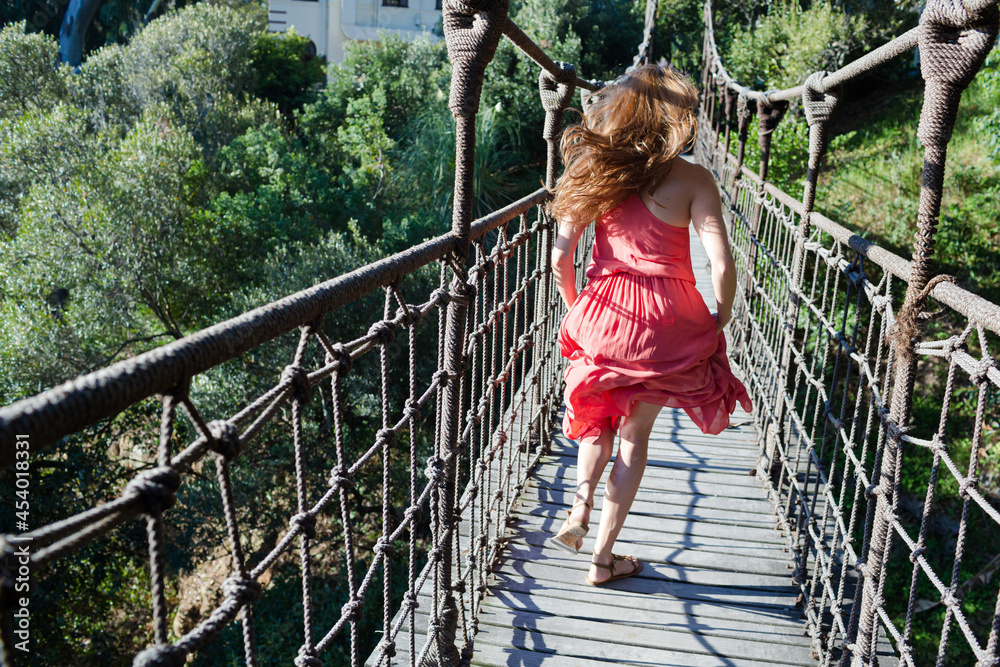 Woman walking on wooden rope bridge