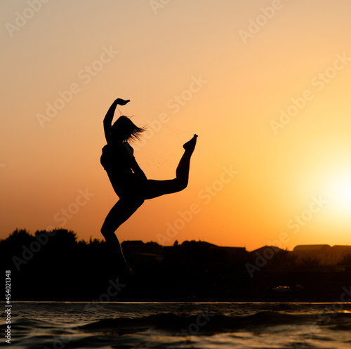 Wallpaper Mural Happy girl having fun and jumps at sunset beach in sunlight. Summer vacation and healthy lifestyle concept Torontodigital.ca
