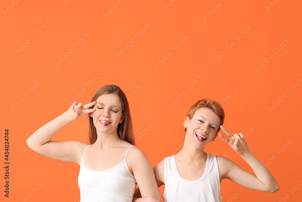Teenagers with dyed eyebrows showing victory gesture on color background Teenagers with dyed eyebrows showing victory gesture on color background