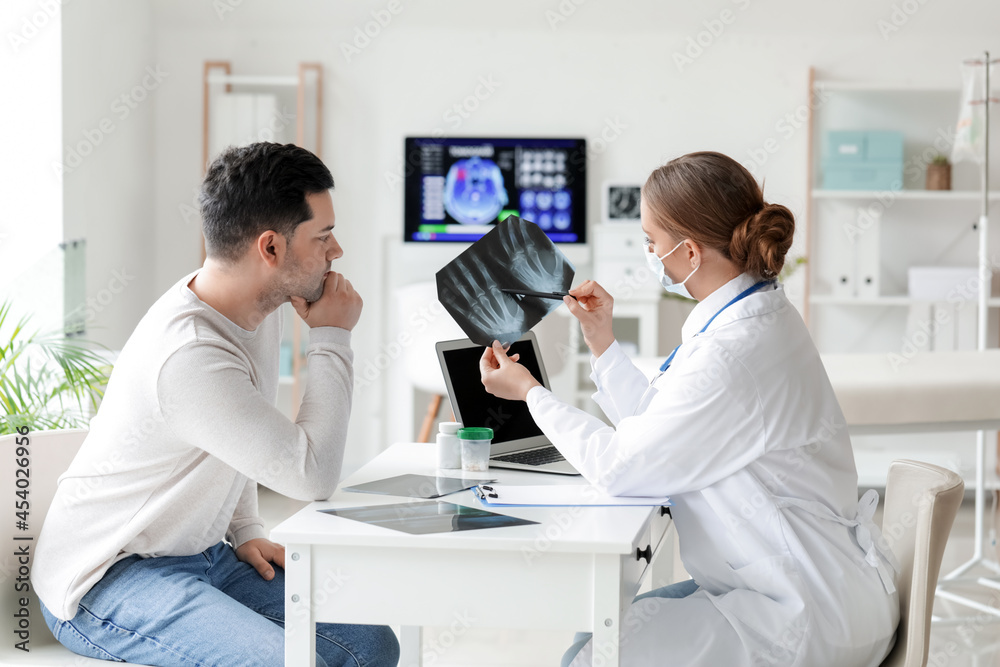 Female doctor showing x-ray scan to patient in clinic Female doctor showing x-ray scan to patient in clinic
