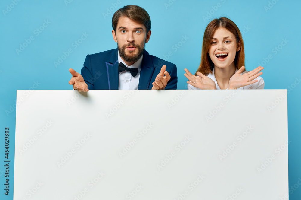 man and woman peeking out from behind white poster billboard blue background man and woman peeking out from behind white poster billboard blue background