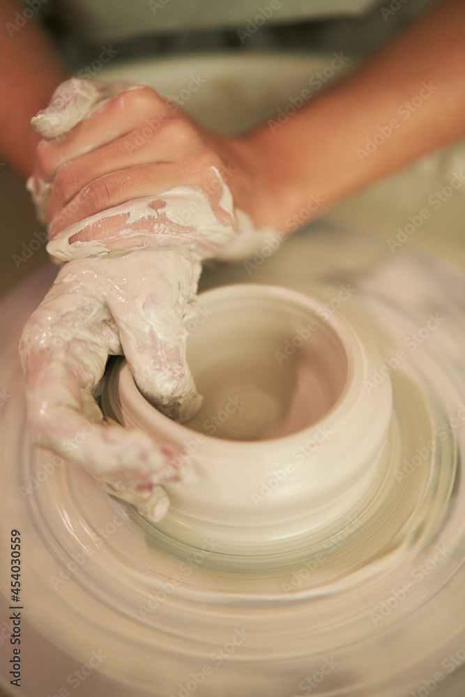 Unrecognizable potter shaping pot from wet clay
