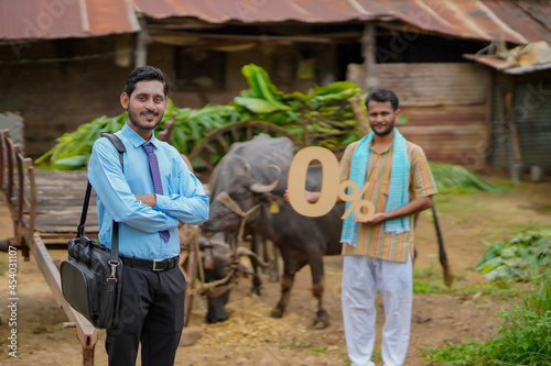 Young indian farmer showing zero percent symbol with agronomist or financier at his cattle farm