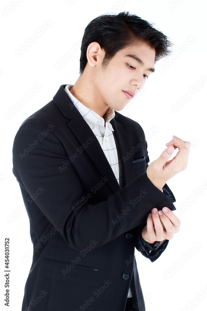 Smiling successful young entrepreneur or businessman in black modern suit, buttoning up a cuff, standing on white background. Smiling successful young entrepreneur or businessman in black modern suit, buttoning up a cuff, standing on white background.