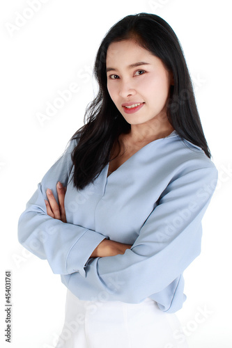 Close-up portrait of a smiling delightful elegant female in a casual light grey apparel with her arms crossed on chest looking at camera on white background.