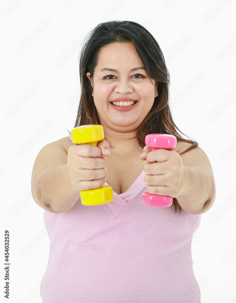 Portrait close up isolated studio shot of Asian happy healthy strong big fat girl stand smile lift pink and yellow dumbbells with two arms in weight lose practice exercise in front white background Portrait close up isolated studio shot of Asian happy healthy strong big fat girl stand smile lift pink and yellow dumbbells with two arms in weight lose practice exercise in front white background