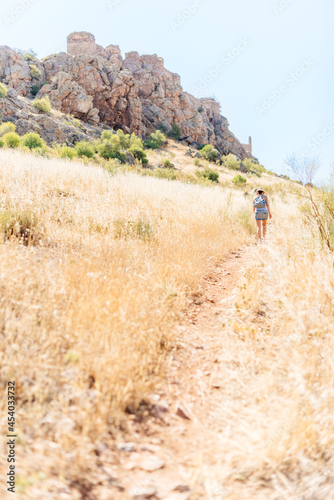 Vertical photo of a woman walking to a hill with a castle. Vertical photo of a woman walking to a hill with a castle.